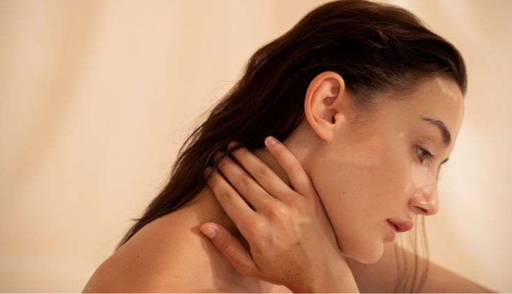 A woman with her hands on her neck. Her skin looks very clear and healthy.