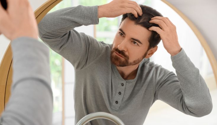 A man looking at his hairline in a mirror